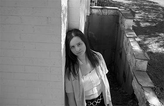 black and white photo taken from above of Emily leaning against a wall