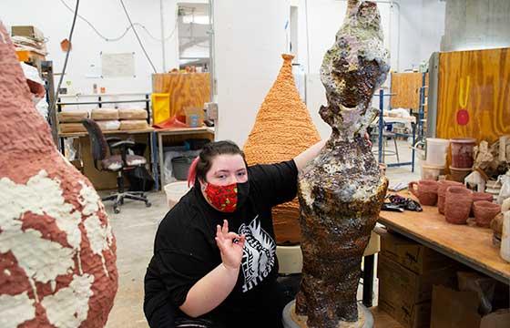 Kit sitting on floor of studio glazing large ceramic object