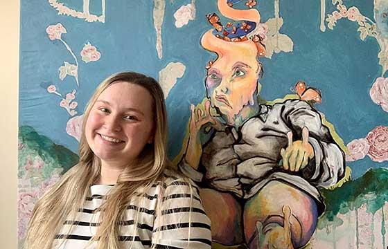 Michaela standing in front of brightly colored painting 