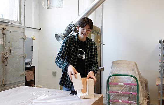 Kyle standing in brightly lit plaster studio opening a plaster mold