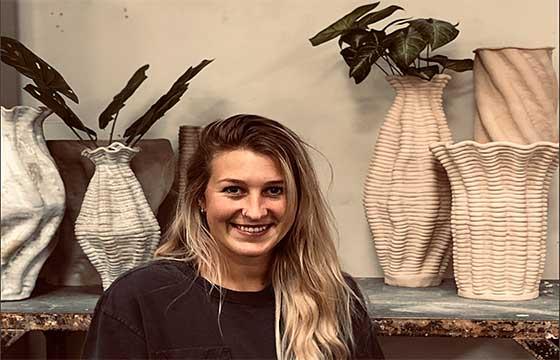 Emma standing in front of a mantle with ceramic vases arranged behind